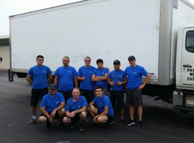 A team of movers standing in front of a moving truck